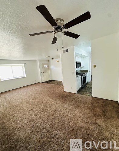 A room with a ceiling fan and carpeted floor.
