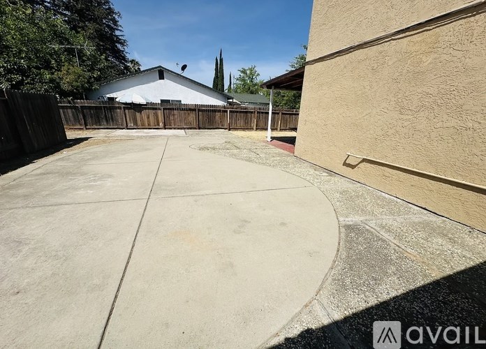A backyard with a concrete patio and a wooden fence.