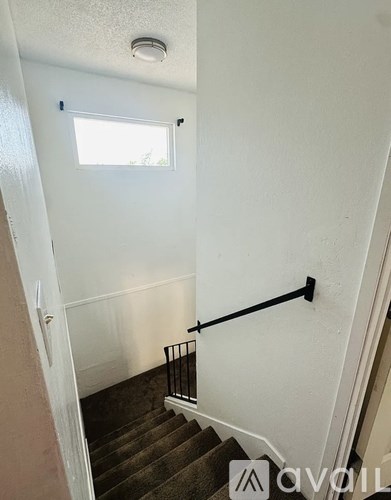 A staircase with a black handrail and a window above it.