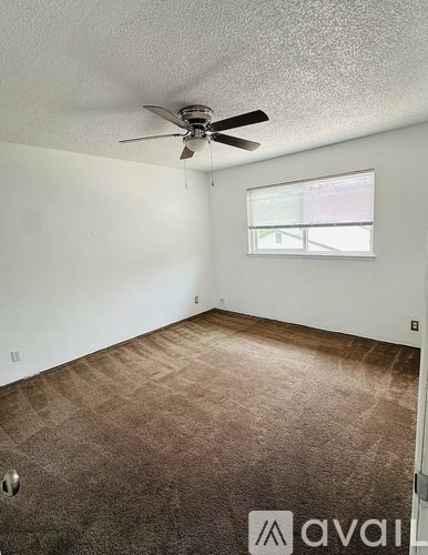 A room with a ceiling fan and carpeted floor.
