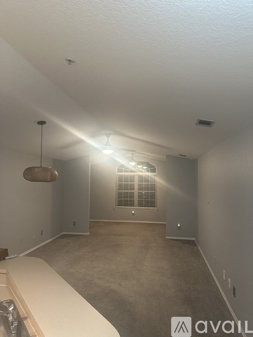 A room with a carpeted floor and a window with blinds.