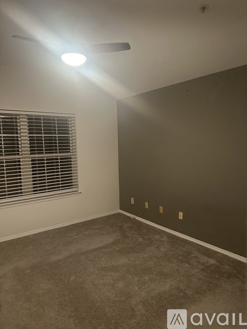 A room with a fan, window with blinds, and a wall with four switches.