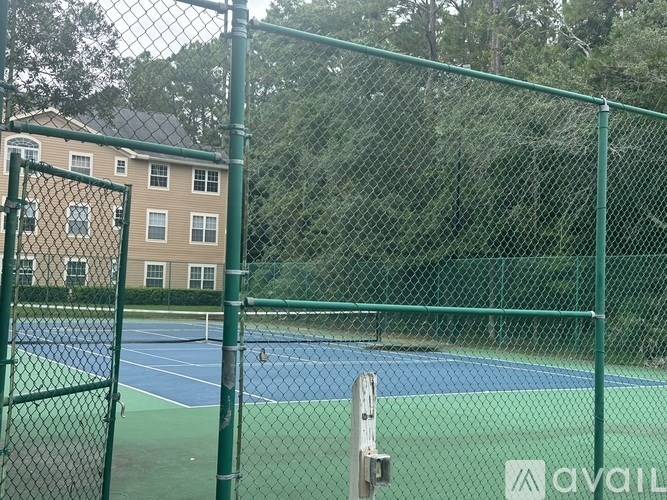 A tennis court surrounded by a green fence.