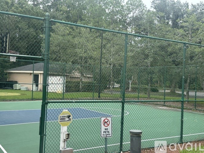A green fence surrounds a basketball court with a sign that says "NO PARKING ANY TIME".
