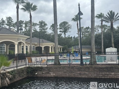 A pool surrounded by palm trees and a building in the background.