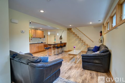 A living room with a black leather couch and a wooden floor.