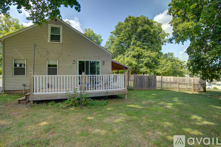 A small house with a porch surrounded by a fence and trees.