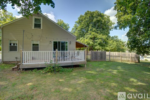 A small house with a porch surrounded by a fence and trees.
