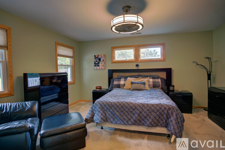 A bedroom with a bed, chair, and a ceiling fan.