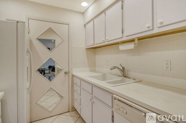 A white kitchen with a fridge and a sink.