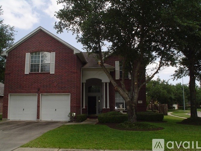A red brick house with a tree in front.