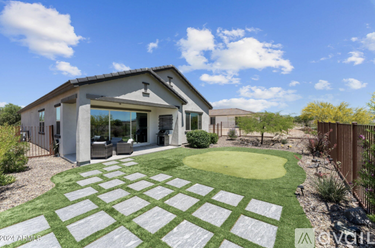 A modern house with a white exterior and a large backyard with a checkerboard patterned lawn.