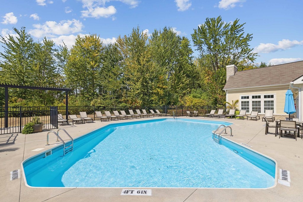 A swimming pool surrounded by a fence and a building in the background.
