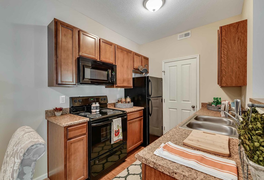 A kitchen with brown cabinets and a black stove top oven.