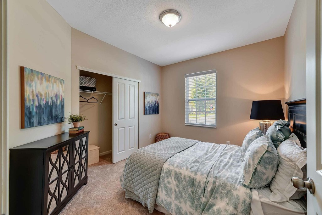 A bedroom with a bed, dresser, and a painting on the wall.