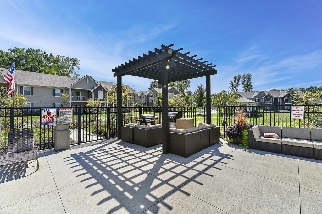 A gazebo is in the middle of a concrete area with a black fence and a flag.