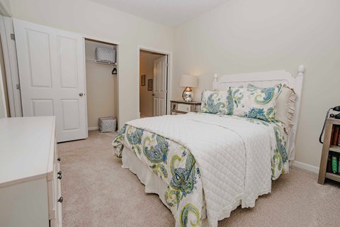 A bedroom with a large bed and a chair.