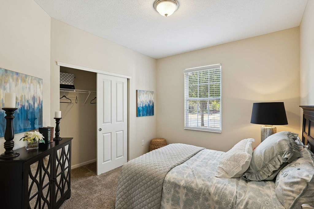 A bedroom with a bed, dresser, and window.