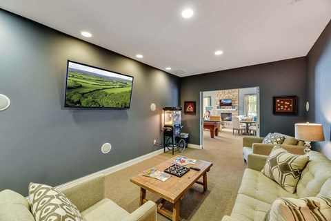 A living room with a large couch, a coffee table, and a television on the wall.