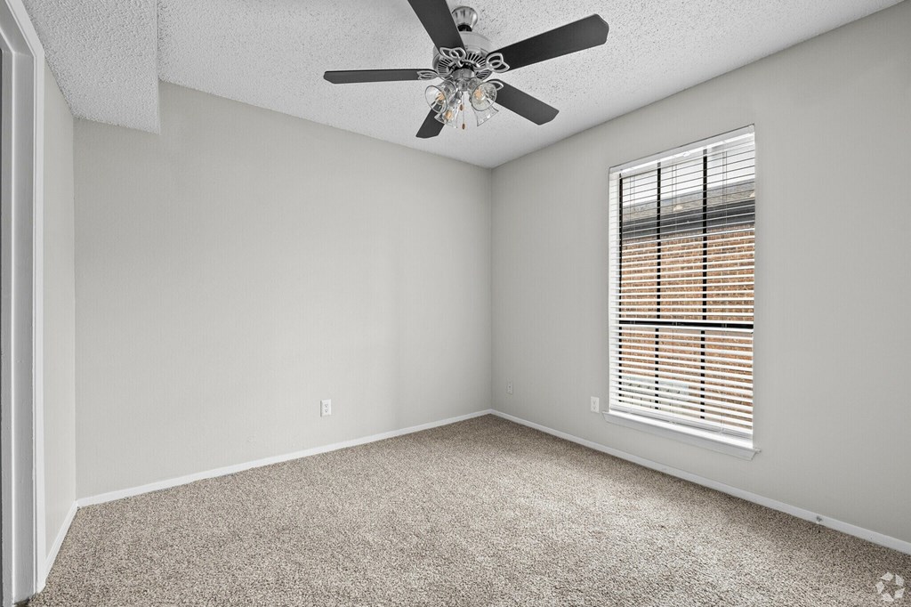 A room with a ceiling fan and a window with blinds.