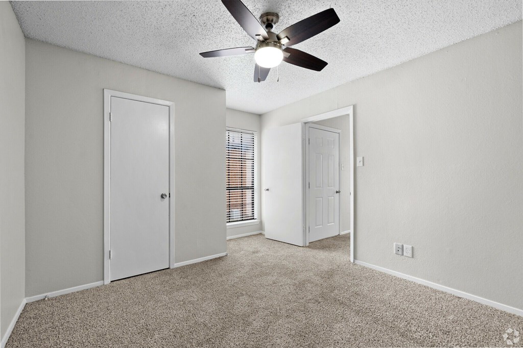 A room with a ceiling fan and carpeted floor.