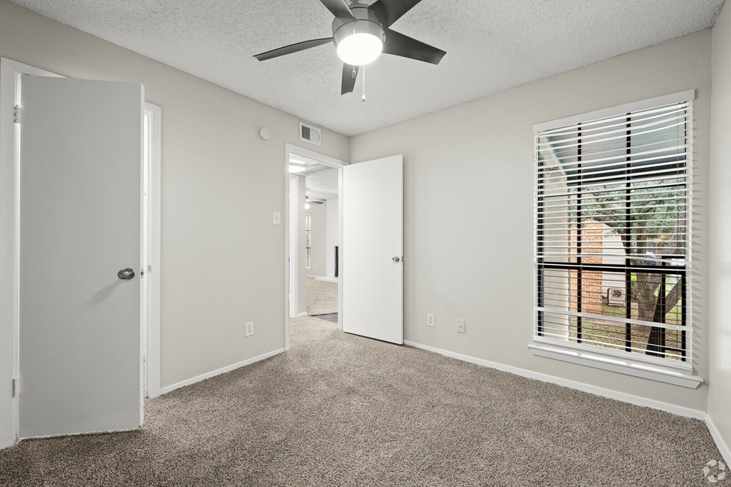 A room with a ceiling fan and a window with blinds.