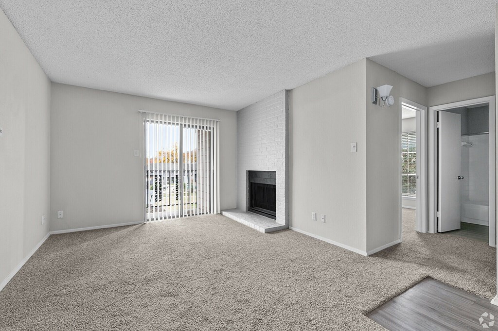 A sparsely furnished living room with a fireplace and sliding glass doors.