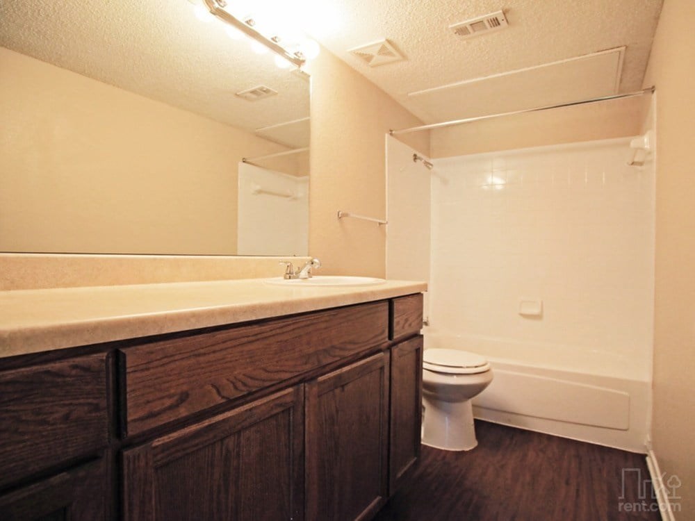 A bathroom with a toilet, sink, and wooden cabinets.