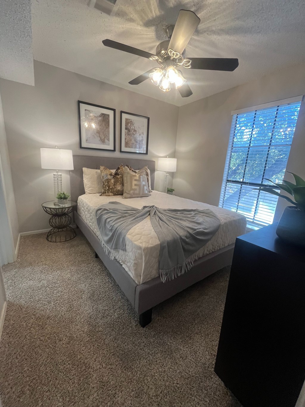 A bedroom with a bed, nightstand, and two framed pictures on the wall.
