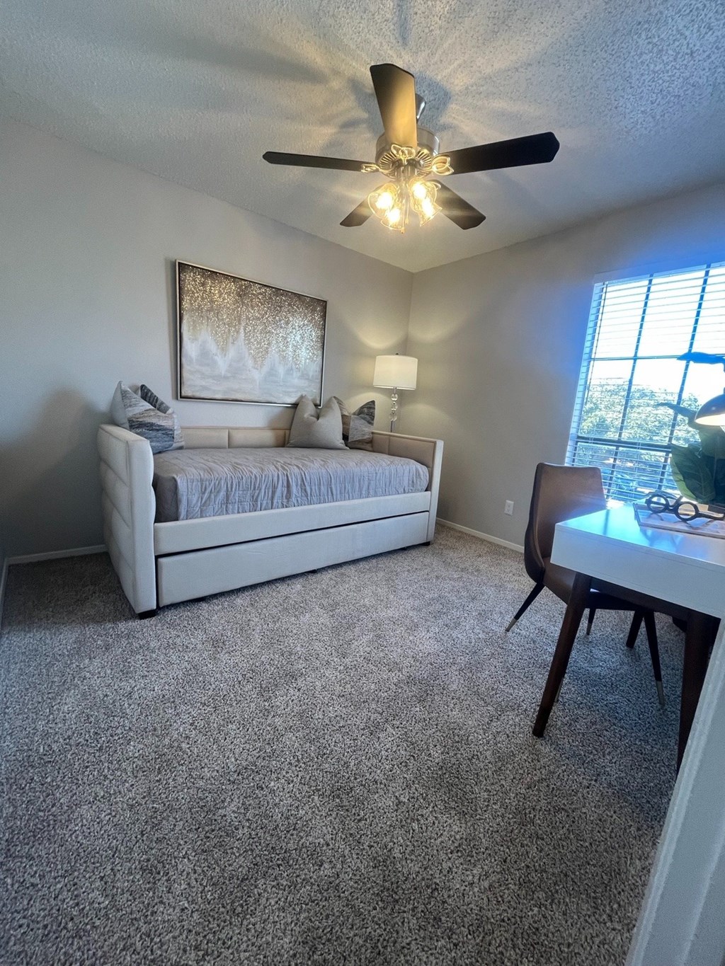 A living room with a couch, a table, and a ceiling fan.
