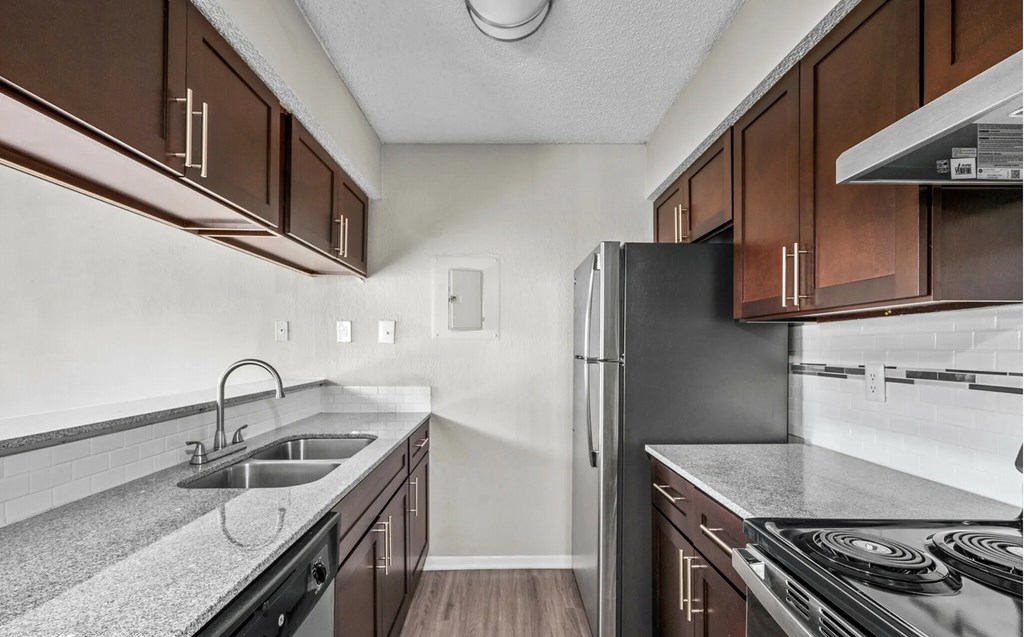A kitchen with brown cabinets and a black refrigerator.