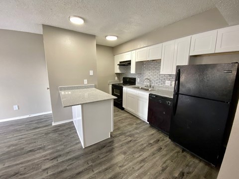 A kitchen with a black refrigerator and white cabinets.
