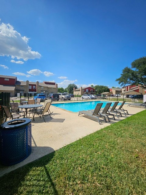 A pool area with chairs and a trash bin.