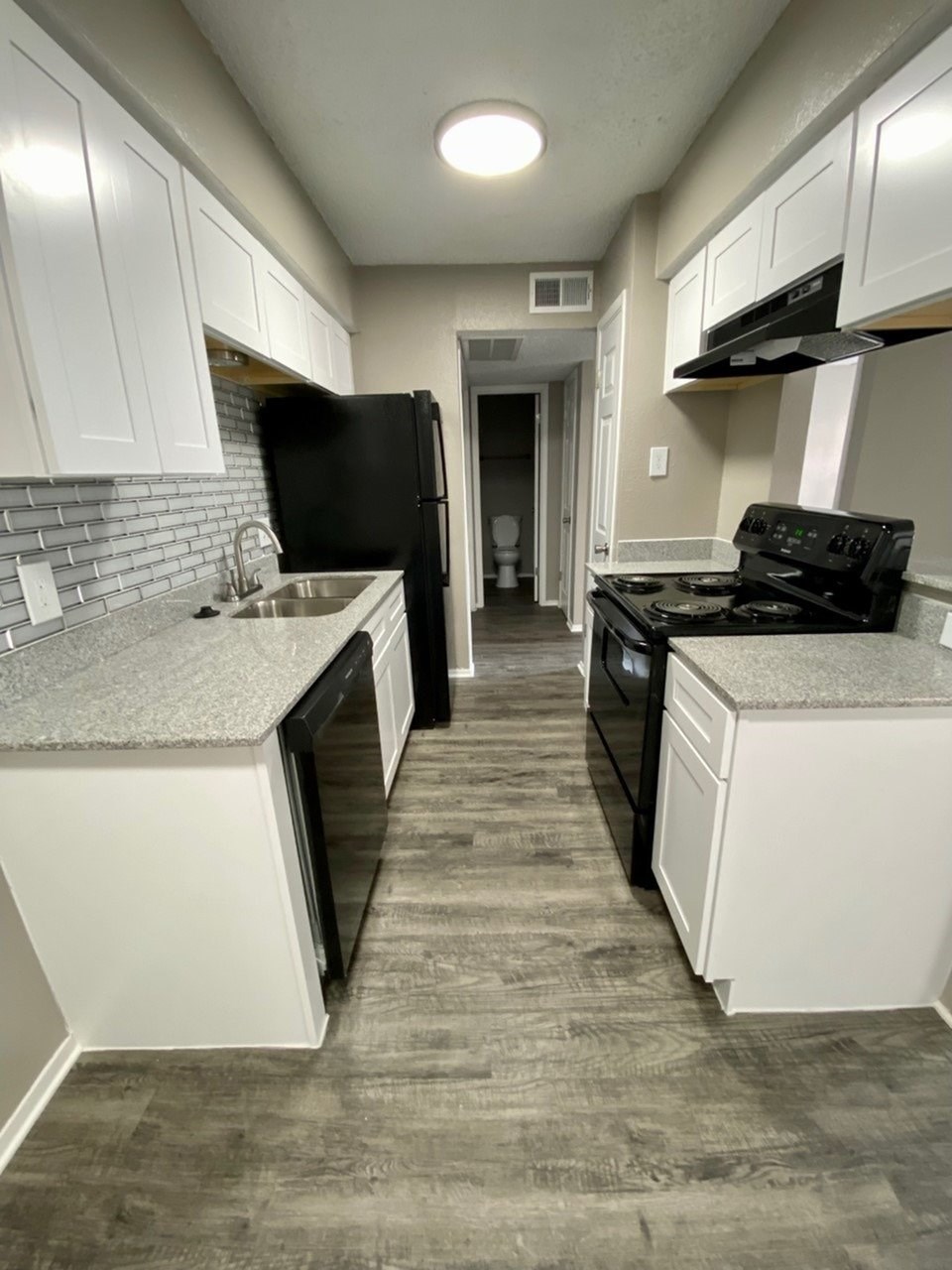 A kitchen with black appliances and white cabinets.