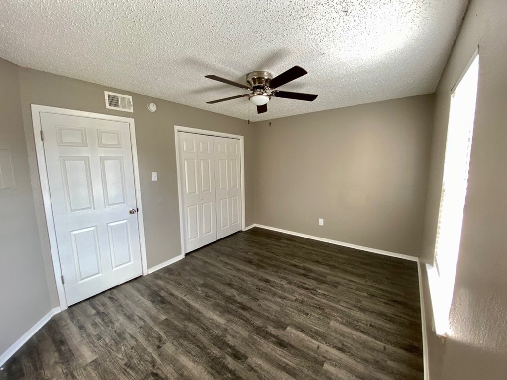 A room with a ceiling fan and two doors.