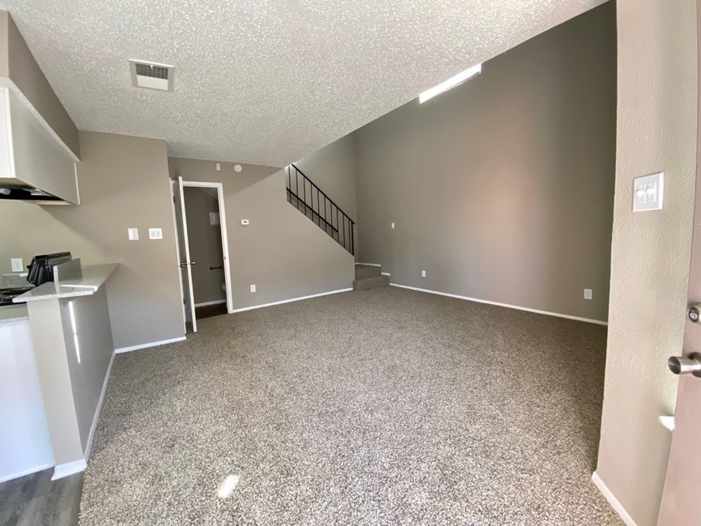 A spacious living room with a staircase leading to the upper floor.