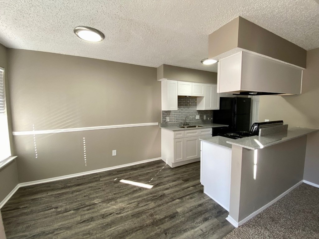 A kitchen with a black fridge and white cabinets.