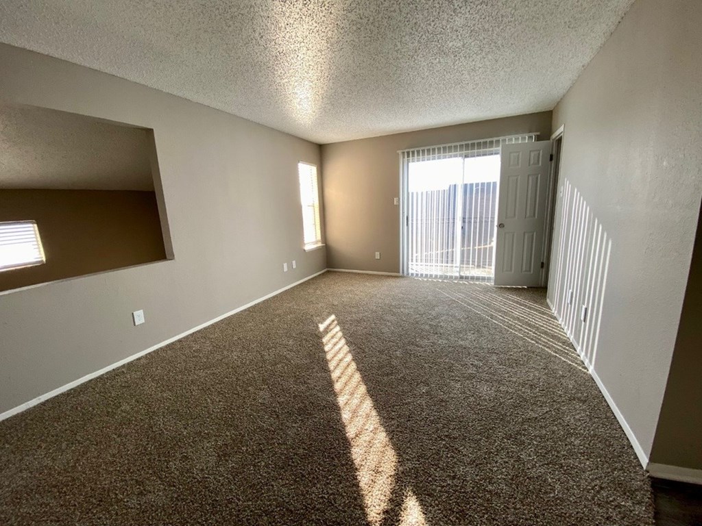 A room with a carpeted floor and a door on the right side.