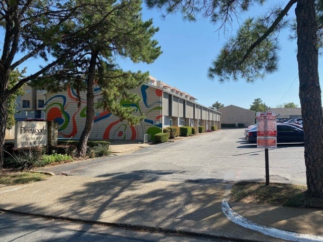 A street view of a residential area with a colorful mural on the wall.