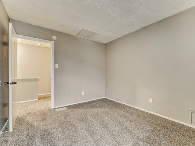 A room with a carpeted floor and a doorway leading to another room.