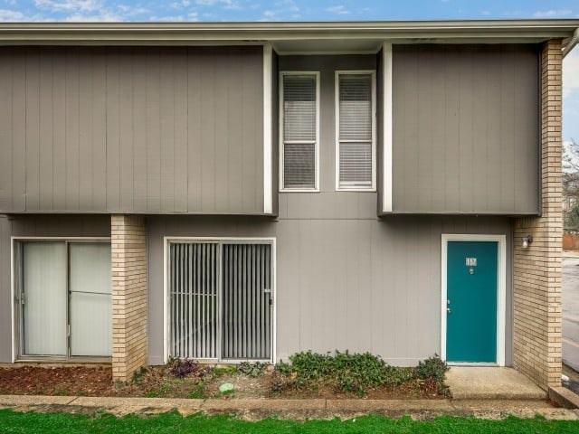 A grey house with a blue door and a window with blinds.