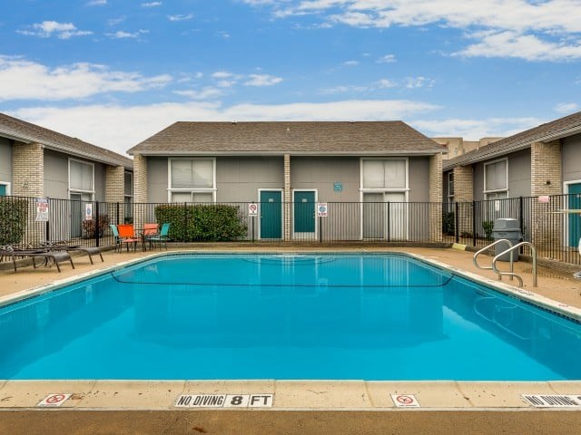 A pool with a no diving sign in front of apartment buildings.