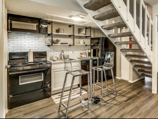 A kitchen with a stove, oven, and bar stools.