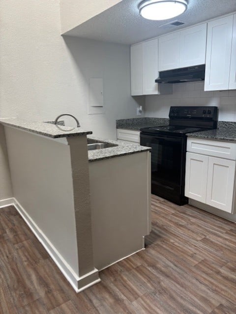 A kitchen with a black stove top oven and white cabinets.