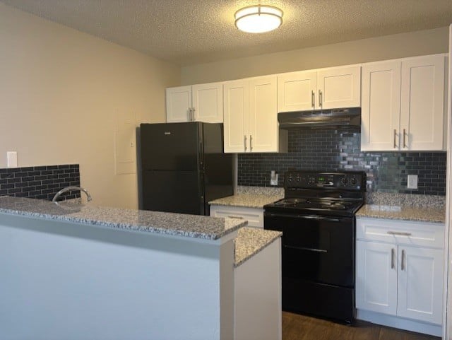 A kitchen with black appliances and white cabinets.