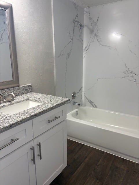A white bathroom with a marble counter top and a white tub.