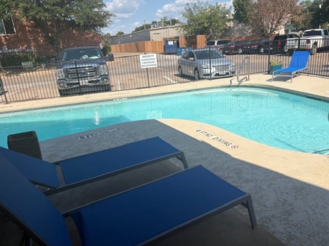 A pool with blue loungers and a sign that says "POOL" on the side.