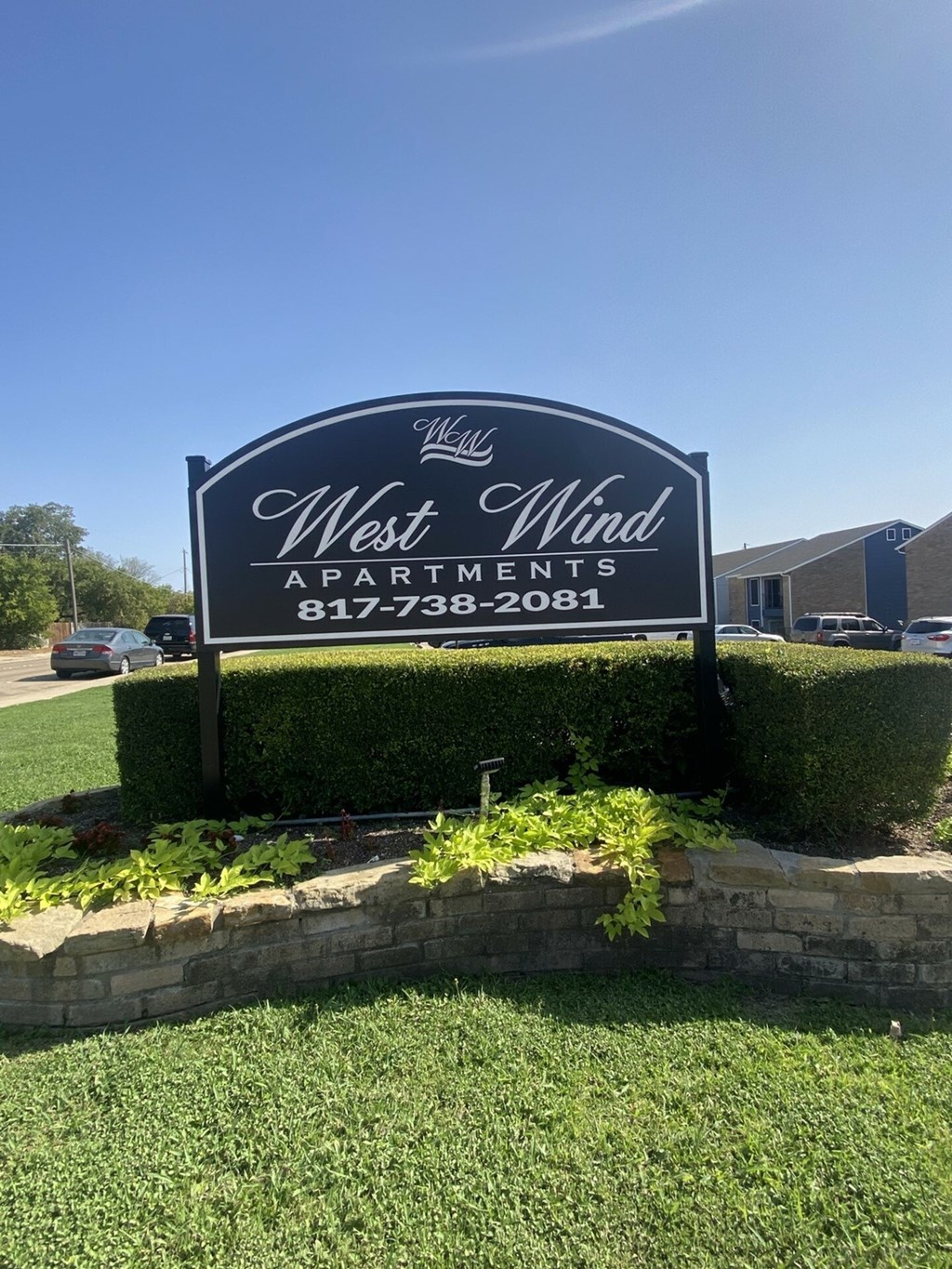 A sign for West Wind Apartments is displayed in front of a building.