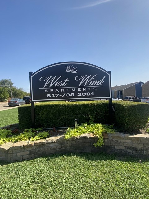 A sign for West Wind Apartments is displayed in front of a building.