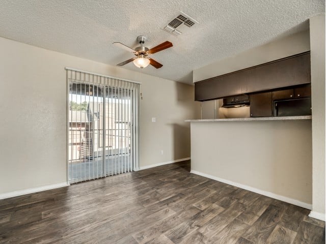 A room with a ceiling fan and sliding glass doors.